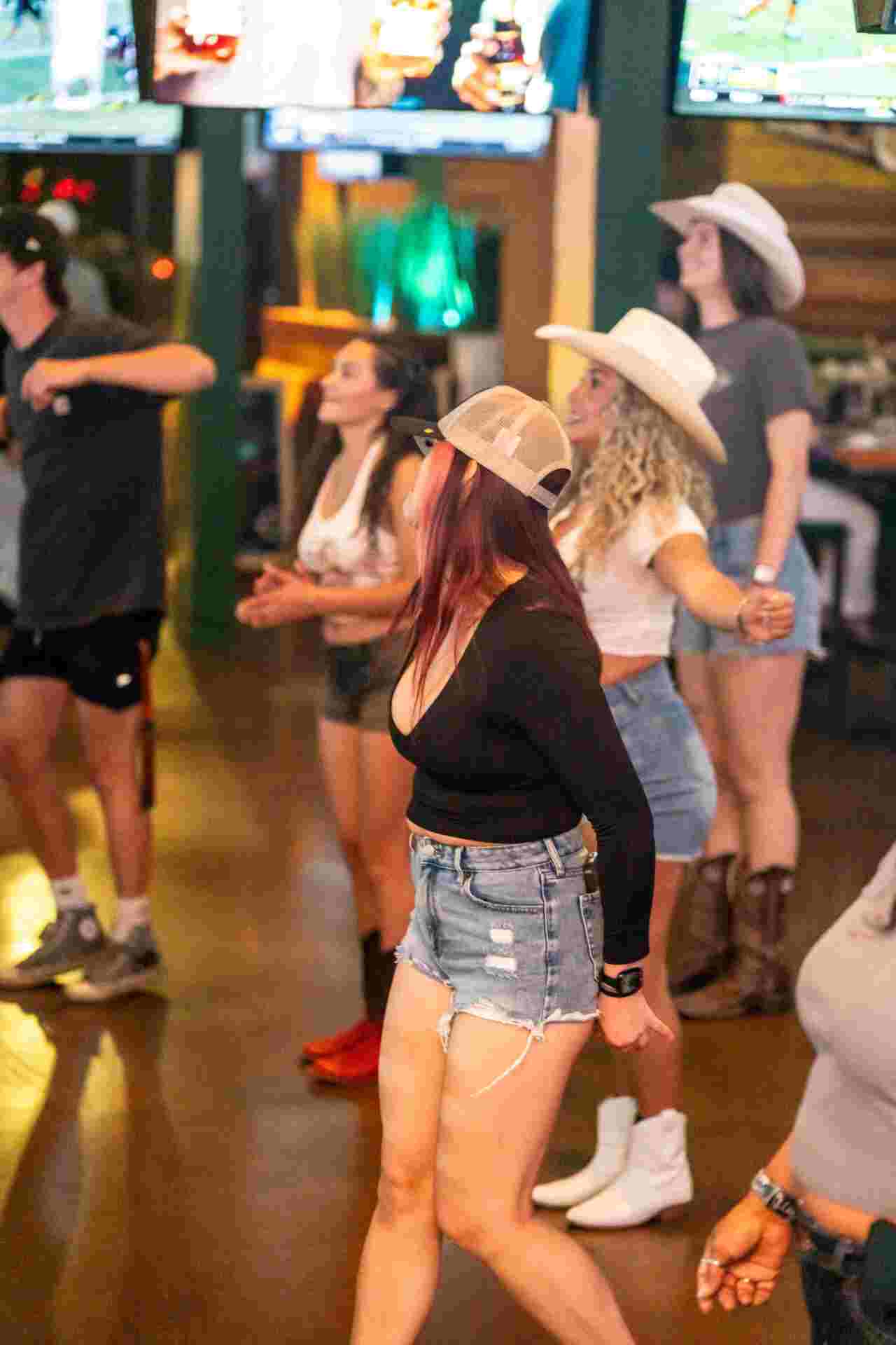 Women line dancing at Backyard Gilbert during Ladies Night, enjoying drinks, music, and a lively bar atmosphere.