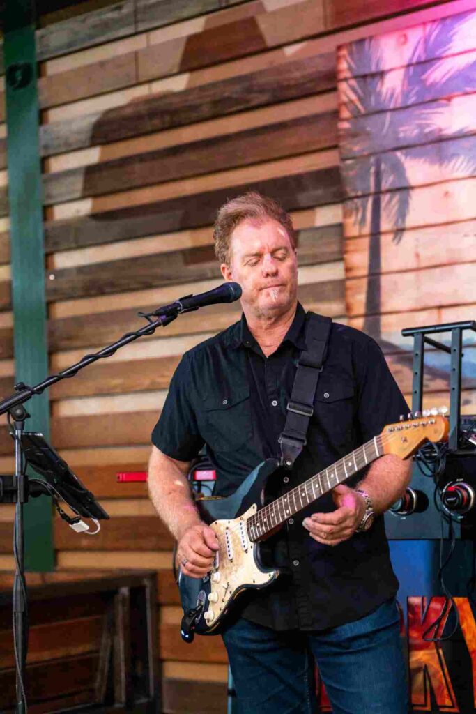 Man playing guitar during live music at Backyard Gilbert, entertaining guests with energetic performances.