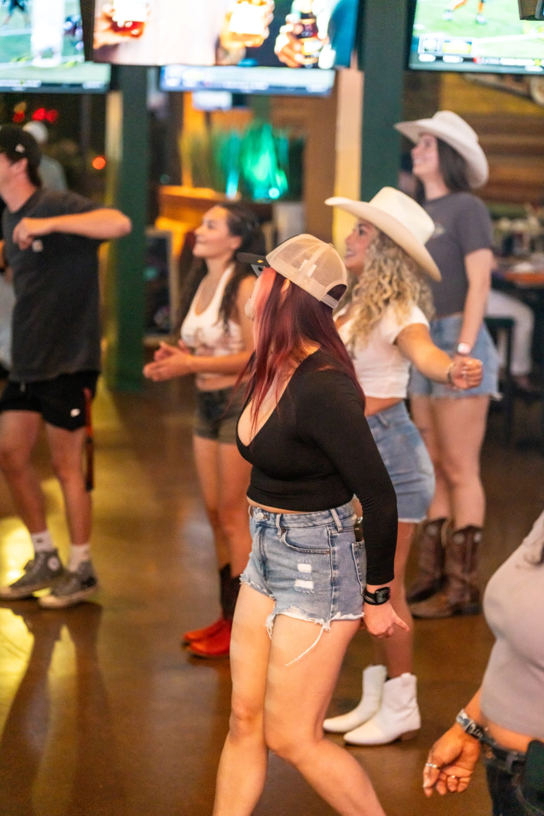 Group of people line dancing in a bar during a country-themed ladies night event
